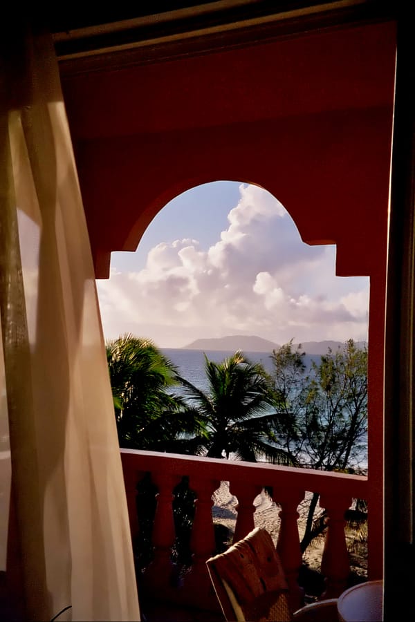 an image of a window, beach and neighboring island